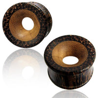 Load image into Gallery viewer, Two round, brown Palmholz Teakholz plugs with a natural tribal pattern and hand-carved smooth centers are shown on a reflective white surface. These Holztunnel feature light and dark tones for a unique, handcrafted look.
