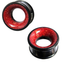 Cargar imagen en el visor de la galería, Two black Holztunnel Eisenholz gauges with red Koralleninlay are shown against a white background. The hand-carved wooden plugs feature flared edges, a hollow center, and a tribal-inspired design.
