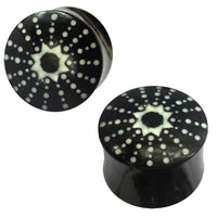 Cargar imagen en el visor de la galería, The Horn Plug schwarz weiß Stern Punkte handgeschnitzt are two black double flared plugs made from hand-carved buffalo horn, each featuring a white starburst dot pattern on the ends for a unique, tribal-inspired look.
