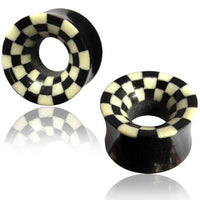 Cargar imagen en el visor de la galería, Two black Horn Flesh Tunnel Schachbrett schwarz weiß plugs with flared ends and a checkered rim design are shown on a white background, featuring reflections beneath them.

