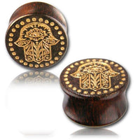 Load image into Gallery viewer, Two dark Holz Plug Poor Mans Hand Tamarind Khamsa plugs with gold-painted, laser-engraved Fatima eye and dotted tribal design, displayed on a reflective surface against a white background.
