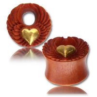 Load image into Gallery viewer, Two red-brown Sawo Holz Tunnel plugs feature antique gold brass heart and angel wing designs, nickel-free, with a tribal organic style, displayed on a white surface with a faint reflection.
