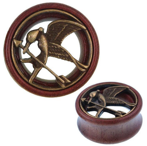 A round Holz Tunnel Schwalbe Pfeil Schnabel Plug features an antique golden finish, tribal design, and elegant brass inlay inspired by the Hunger Games, with a bird holding an arrow in its beak.