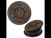 Load image into Gallery viewer, The Schraub Plug Sonnenuhr Acrylic Tunnel Expander Piercing features an antique gold brass inlay with a raised sun motif and runes, shown from two angles on a white background.
