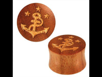 Load image into Gallery viewer, The &quot;Holz Plug braun handgeschnitzt Lasergravur Anker Sterne gold bemalt Tunnel Expander&quot; zeigt ein handgeschnitztes, rundes Plug: Ein Anker mit Schlange und drei goldenen Sternen ist per Lasergravur verziert; einer steht, einer liegt zur Formansicht.
