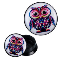 Load image into Gallery viewer, A round black Acryl Schraub Plug with a thick owl design in blue, yellow, and pink. One Piercing Ohrschmuck stands upright to show the front, while another lies on its side displaying the back.
