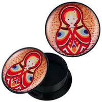 Load image into Gallery viewer, A round black container with a lid showing a vibrant Matroschka design in red, yellow, and blue, resembling the Schraub Plug Acryl rot gelb blau Matroschka Piercing Ohrschmuck. The lid appears both on and next to the open container.
