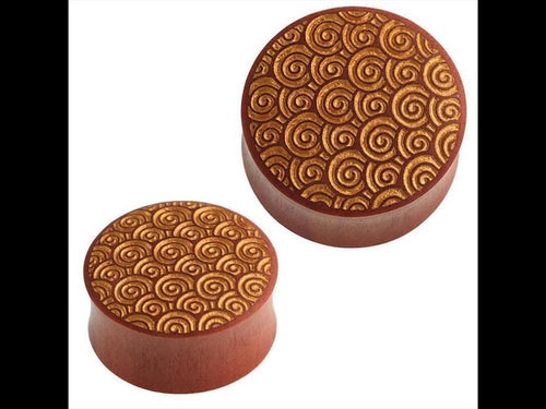 Two round Holz Plug goldene Spiralen Kreis Sawoholz rotbraun Gravur containers, one larger than the other, with golden spiral patterns on their lids are shown side by side against a white background.