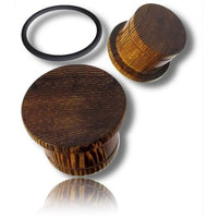 Load image into Gallery viewer, Two Flat Top Plug Siamea Holz single flared tunnels with maserung (grain pattern) are shown—one upright, one on its side—beside a black Gummiring (rubber ring) on a white background, all casting soft shadows.
