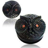 Load image into Gallery viewer, A round, black hand-carved Holz Plug Eule with a lid shaped like an owl’s face, featuring textured feathers and brown eyes, is shown from two angles on a white background.
