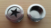 Load image into Gallery viewer, Two round metal objects on wood; the left is an Edelstahl Tunnel Plug Schraubplug Stern schwarz silber Scheibe ribbed Piercing with a cut-out star, while the right is open, showing its hollow interior.
