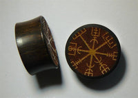 Load image into Gallery viewer, Two round, dark Plug Arangholz Wikinger Kompass Inlay double flared plugs are shown with a gold Viking compass symbol on the flat surface, displayed on a white background.
