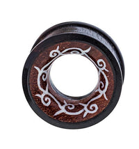 Load image into Gallery viewer, The Holz Tunnel Bone Inlay Kranz Spiralen Tribal Plug is a hand-carved, circular expander made from Sonoholz and Tamarindenholz, featuring a hollow center and intricate light-colored vine and swirl designs around the edge.
