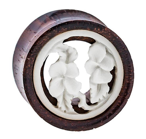 The Holz Plug Tamarindenholz Tunnel features a white bone inlay with a tribal floral design, showcasing two detailed flowers and leaves within the round frame.