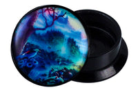 Load image into Gallery viewer, A round, black Schraub Plug Acryl Paradies Garten blau grün gelb Piercing Ohrschmuck features a lid with a vibrant, fantasy forest design in blue, green, and yellow tones. The slightly open lid reveals an empty space for storing Ohrloch Schmuck.
