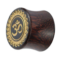 Load image into Gallery viewer, A hand-carved Tamarind wood plug with a flared shape, gold-painted Om design, and decorative laser-engraved border inspired by tribal organic Blume motifs.
