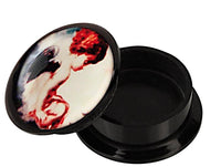 Load image into Gallery viewer, A black Schraub Plug Acryl &quot;Engelchen sitzend&quot; container with its lid slightly open, showing colorful abstract face art in red, white, and black—perfect for storing your Piercing Ohrschmuck.
