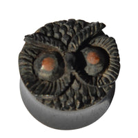 Load image into Gallery viewer, The &quot;Holz Plug Eule schwarz handgeschnitzt braune Augen&quot; is a small, round wooden plug with an owl’s face, brown eyes, and feather details—an elegant organic Schmuck piece shown on a plain white background.
