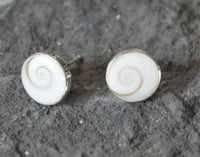 Load image into Gallery viewer, A pair of Ohstecker Shiva Auge rund in 6mm, 10mm, or 12mm with white shells and natural spiral patterns, set in 925 Silber, displayed on a textured gray stone surface.
