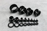 Load image into Gallery viewer, A selection of Metalltunnel Tunnel Chirurgenstahl Unisex Edelstahl Plug schwarz Rand Expander Piercings is neatly arranged on a light gray textured surface, organized by size from largest to smallest.
