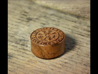 Load image into Gallery viewer, A Flesh Plug Teakholz Vegvisir Runen Ring double flared with Norse runes and a Vegvisir compass on top rests on a textured, light wooden surface.

