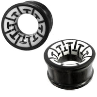 Cargar imagen en el visor de la galería, Two black &quot;Tribal Holz Tunnel&quot; ear plugs, hand-carved from ironwood with white bone inlays featuring a geometric black pattern. These cylindrical plugs blend modern style with traditional design.
