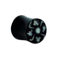 Cargar imagen en el visor de la galería, The Horn Plug schwarz Bone Inlay weiß Distel Muster features a black cylindrical shape with a striking white thistle-style bone inlay on one end, shown at an angle against a plain white background.
