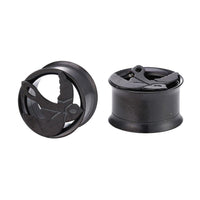 Cargar imagen en el visor de la galería, Two Tunnel Plug Edelstahl Schraubplug dünn schwarz plugs, each featuring a raised Friedenstaube motif with outstretched wings. One plug stands upright while the other lies on its side.
