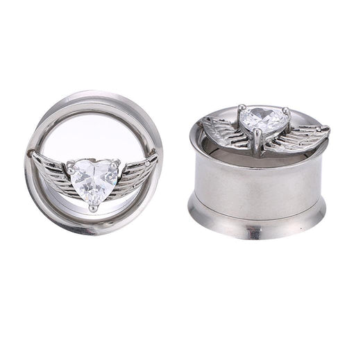 Two Edelstahl Tunnel Plug Flügel Herz Stein facettiert Schraubplug double flared ear gauges are shown: each features a heart-shaped faceted gem with metal wings, displayed from a front and an angled view. The design is sleek and decorative.