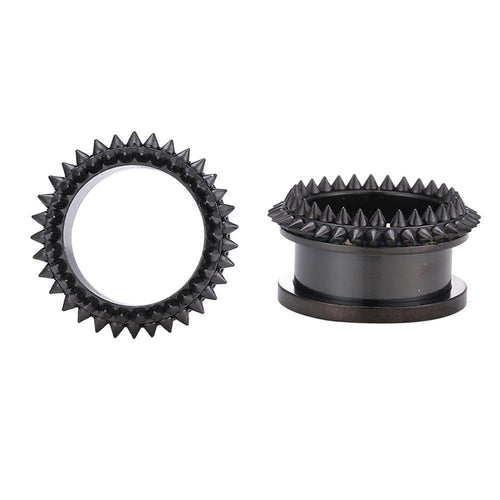 Two black Edelstahl Tunnel Plug Schraubplug mit dünner Form und kegelförmigen Spitzen-Nieten sind vor weißem Hintergrund zu sehen: einer aufrecht stehend in Ringform, der andere flach liegend mit sichtbarem zylindrischem Sockel.