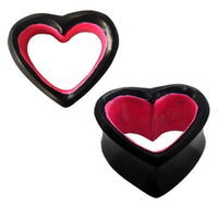 Cargar imagen en el visor de la galería, Two hand-carved Sonoholz Holztunnel Herz plugs, in black with pink inner edges, display their hollow heart design—one upright, one on its side—highlighting the unique tribal style of these ear plugs.
