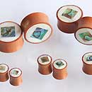 Cargar imagen en el visor de la galería, Small wooden spools, inspired by the Organic Sabaholz Plug Paua Abalone design, feature tiny bird and fish images with white tops and are arranged in groups on a white surface.
