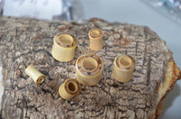 Cargar imagen en el visor de la galería, Six heller Tunnel Crocodile Holz dunkles Rangholz Inlay Tunnel Rim cylinders in different sizes are displayed on rough tree bark, with a blurred background.
