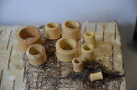 Cargar imagen en el visor de la galería, Several smooth, cylindrical Holz Flesh Tunnel Krokodilholz hell leicht konvex double flared rings in various sizes are arranged on birch bark, highlighting their natural light wood color and rustic handmade craftsmanship.
