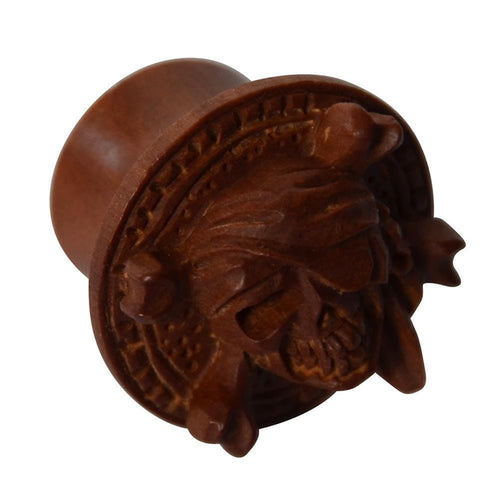 The Holz Plug Pirat Totenkopf handgeschnitzt rotbraun double flared features a hand-carved pirate skull with crossed bones and a round, decorative border in red-brown wood.