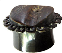 Load image into Gallery viewer, A close-up of the &quot;Horn Plug Blumenform dunkelbraun Rohhorn double flared,&quot; featuring a wide, dark brown band with a flat, carved top and decorative holes. The polished surface highlights the natural horn texture.
