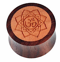 Load image into Gallery viewer, The &quot;Holz Plug Om Blume Gravur zweifarbig handgeschnitzt braun&quot; features a hand-carved Om flower design on a round, polished wood plug with an eye-catching two-tone brown finish.
