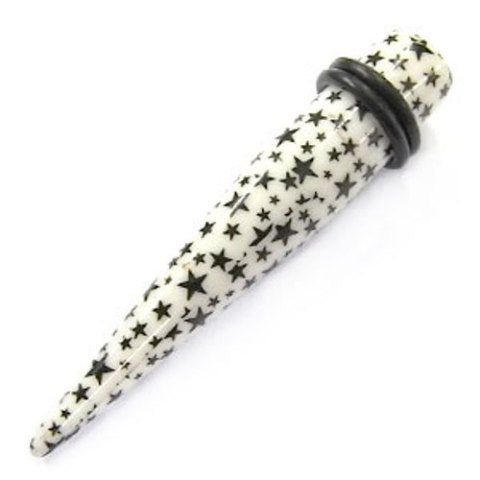 The Sterne Piercing Expander Dehnungsstab is a white, straight unisex ear stretching stick with black star patterns in various sizes and a black rubber O-ring near the wider end.