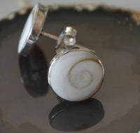 Load image into Gallery viewer, A close-up of the Ohstecker Shiva Auge rund 925 Silber, available in 6mm, 10mm, and 12mm sizes, showcases a round white shell with a natural spiral pattern set in sterling silver on a glossy dark surface.
