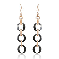 Load image into Gallery viewer, These Ohrringe Ohrhänger Damen aus Edelstahl und Keramik bestehen aus drei schwarzen ovalen Ringen, verbunden mit goldfarbenen Elementen und nickelfreien Haken für angenehmen, rostfreien Tragekomfort.
