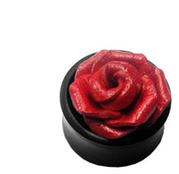 Cargar imagen en el visor de la galería, A black circular Leder Holz Plug by Sonoholz features a detailed red 3D rose atop, resembling a tribal tunnel. This unisex ear jewelry is displayed against a plain white background.
